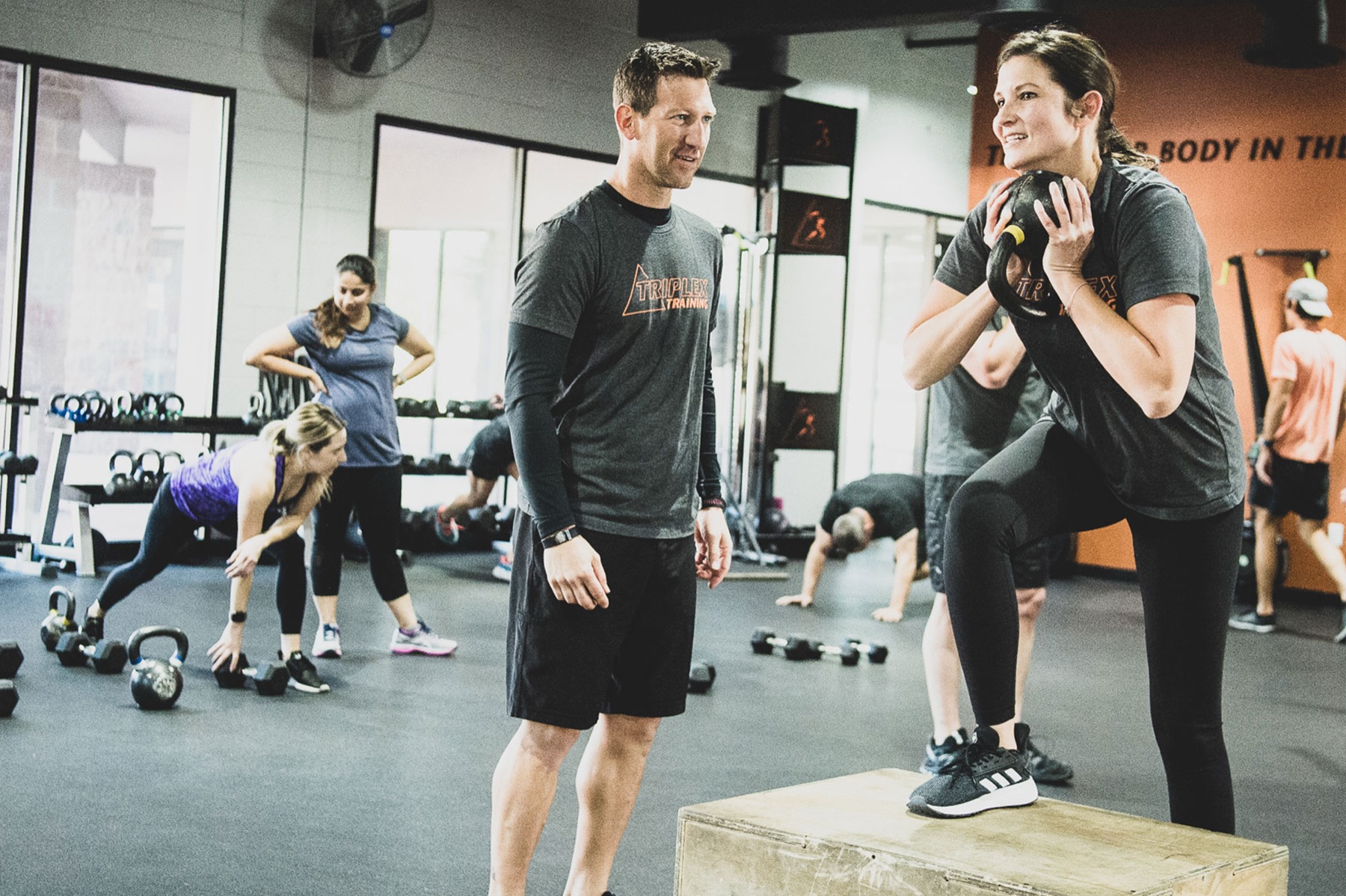 A Triplex coach working one-on-one with a client on a box step-up